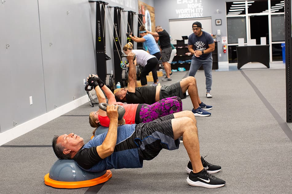 Coastal Fitness members doing KB straight arm pullovers during a group training session