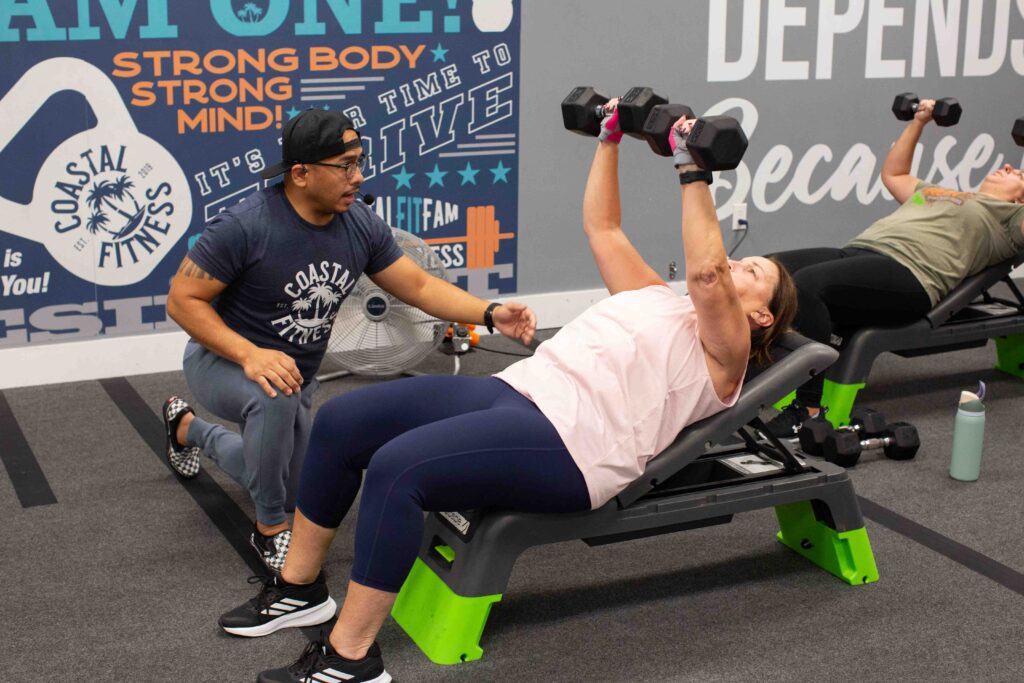 Coastal Fitness coach guiding 55 and older member through strength training workout
