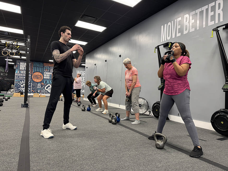 Coastal Fitness coach guiding 55 and older members through strength training workout
