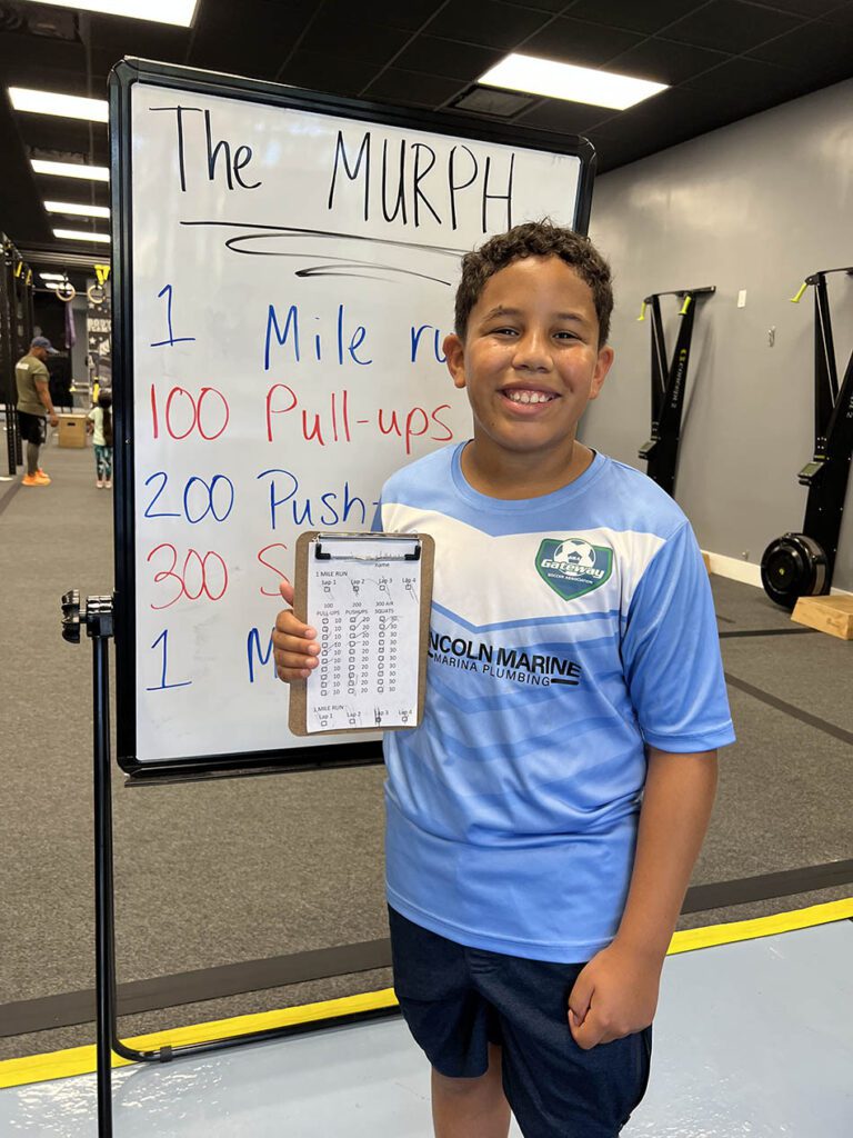 Children of members proudly show their completed Murph check sheets